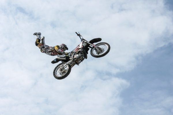 Hoppande motorcykel med förare hängande
